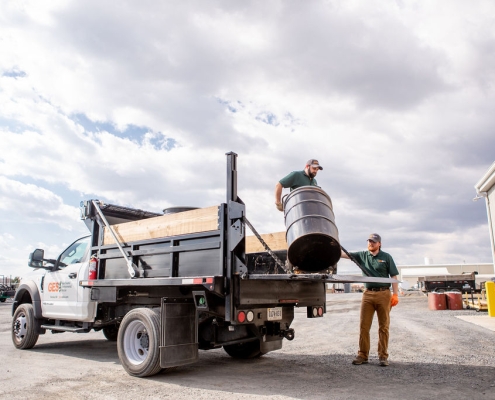Environmental services technicians taking barrels off of a truck